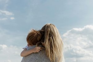 Boy holding onto his mum as she carries him over her shoulder
