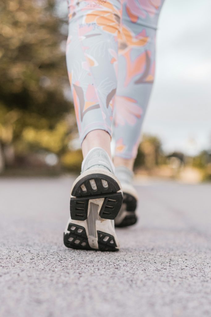 woman in sneakers walking on the footpath